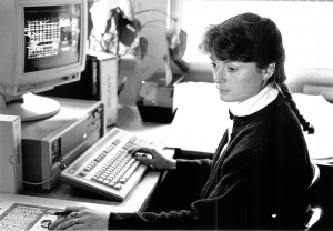 black and white photograph, woman with hair braid using old computer
