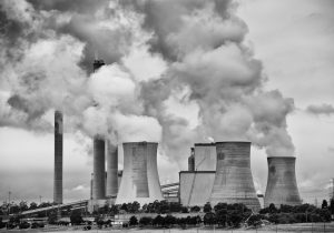 Black and white photograph, coal power station with smoke coming from large chimneys